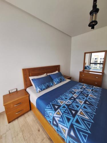 a bedroom with a bed with a blue comforter and a window at Apartment place italie in Rabat