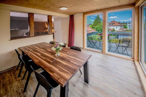a dining room with a wooden table and some windows at Swiss Inn & Apartments in Interlaken