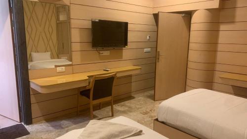a bedroom with a desk and a bed and a television at Dwarka Palace Luxury Rooms, Madurai - Trichy Bye Pass, Madurai in Madurai