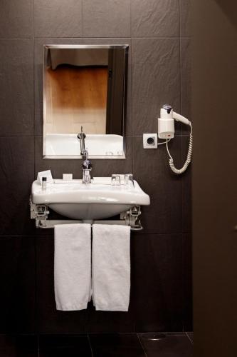 a bathroom with a sink and a mirror and towels at Hotel Pax Guadalajara in Guadalajara