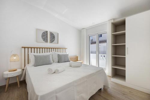 a white bedroom with a large bed with towels on it at Old Town Apartments Sea View in Lagos