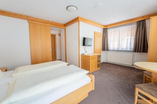 a bedroom with a bed and a desk and a tv at Hotel Garni Krumbach in Damuls