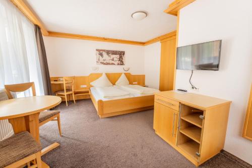 a hotel room with a bed and a table at Hotel Garni Krumbach in Damuls