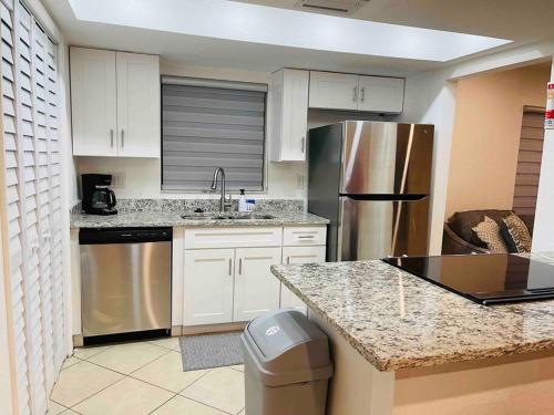 een keuken met witte kasten en een roestvrijstalen koelkast bij Modern Sun N’ Lake Villa - Self Check-In in Sebring