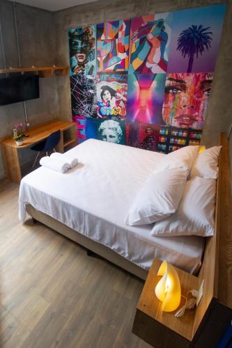 a bedroom with a large white bed with a colorful wall at Lobie Armazém São Joaquim in Rio de Janeiro