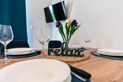 a table with glasses and purple tulips in a vase at Apartments MENA in Bibinje