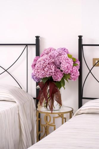 a vase of purple flowers on a table between two beds at La Tenuta Va Oltre in Bovolenta