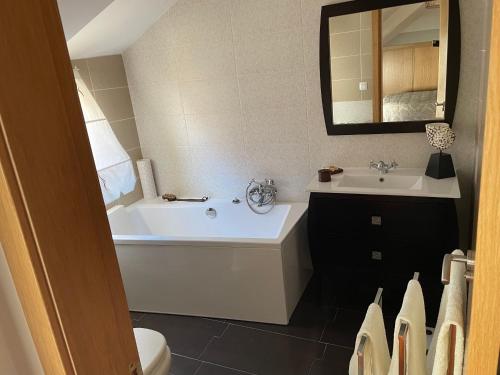 een badkamer met een wit bad en een wastafel bij Sweet Home in Moaña