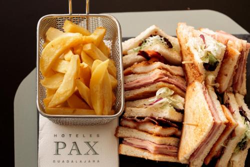 a sandwich and french fries on a plate with a box of chips at Hotel Pax Guadalajara in Guadalajara