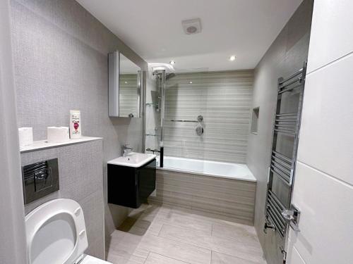 a bathroom with a tub and a toilet and a sink at Massive Flat Near Greenwich Park( with office) in London
