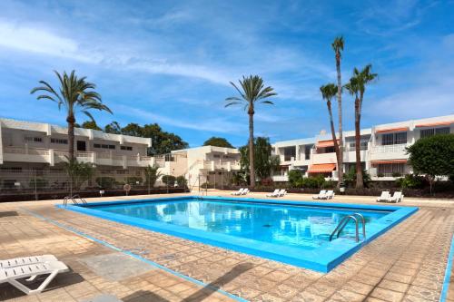 uma piscina com palmeiras e edifícios em Elegant and Cozy Studio with Pool Chaparral 341 em Costa Del Silencio