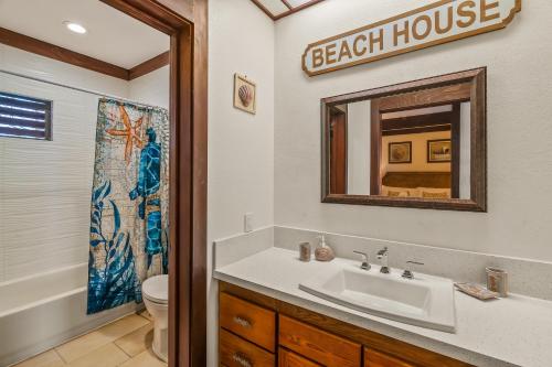 a bathroom with a sink and a toilet and a mirror at Beautiful Poipu AC, Walk to Beach, Pool and Tennis KP117 in Koloa