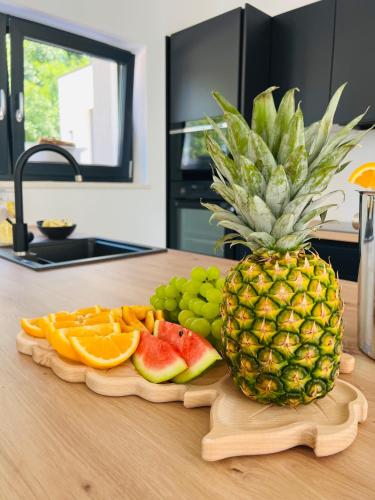a pineapple and fruit on a cutting board on a kitchen counter at Vila Prisunca jacuzzi & swimming pool in Pazin