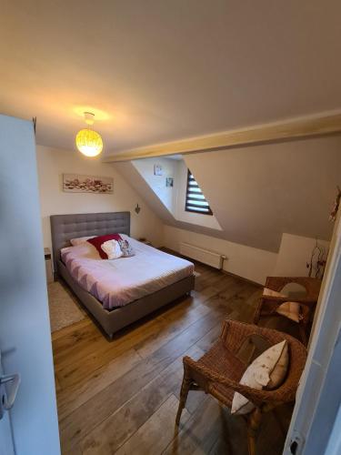une chambre mansardée avec un lit et une chaise dans l'établissement La Brise, à Saint-Maurice