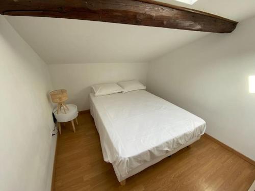 a bedroom with a white bed and a table at Grand appartement jardins de la Fontaine in Nîmes