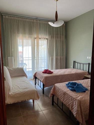 Cette chambre comprend 3 lits et une fenêtre. dans l'établissement Lazaros family home, à Néa Michanióna