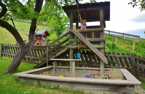 a little girl playing in a wooden play house at Ferienwohnungen Perhofer in Birkfeld