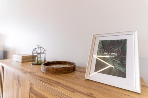 einem Bilderrahmen auf einem Holztisch mit einer Pflanze in der Unterkunft Ocean View Flat in Câmara de Lobos