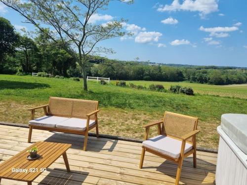 2 chaises et une table sur une terrasse en bois dans l'établissement La Bergerie, à Évellys
