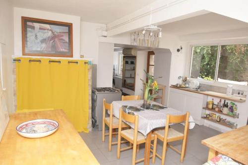 une cuisine avec une table à manger et une porte jaune dans l'établissement Maison avec jardin centre historique, à Agde