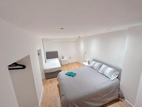 a white bedroom with a bed and a chair at Massive Flat Near Greenwich Park( with office) in London