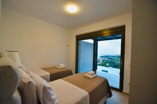 a hotel room with two beds and a large window at Blue Lilac Villas in Parga