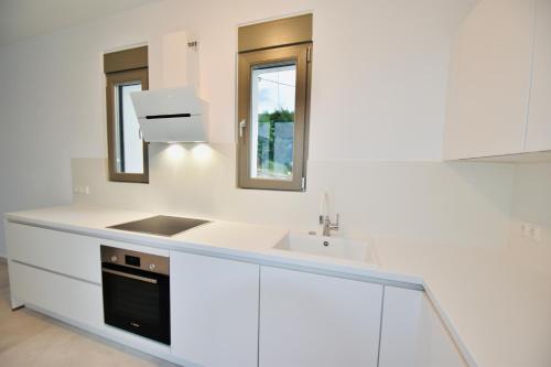 uma cozinha com armários brancos e um lavatório e espelho em Blue Lilac Villas em Parga