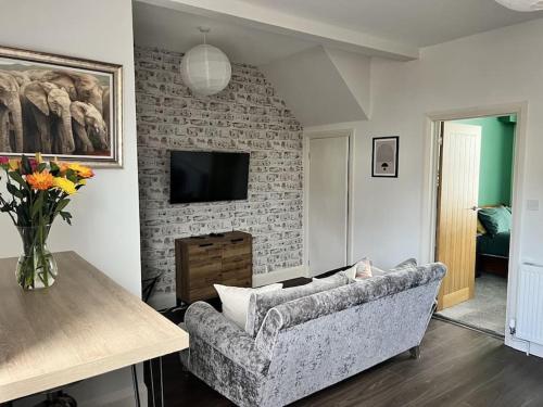 ein Wohnzimmer mit einem Sofa und einem TV in der Unterkunft Ground floor flat in Keynsham