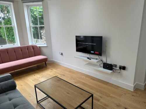 a living room with a couch and a flat screen tv at Massive Flat Near Greenwich Park( with office) in London
