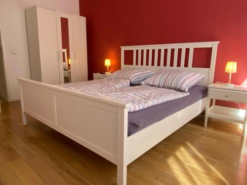 ein weißes Bett in einem Zimmer mit einer roten Wand in der Unterkunft Fischbach Apartment in Saarbrücken