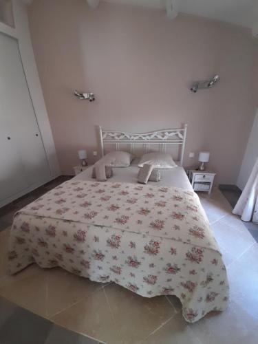 una camera da letto con un grande letto con un copriletto floreale di Villa le Bosquet en Luberon. a Ménerbes
