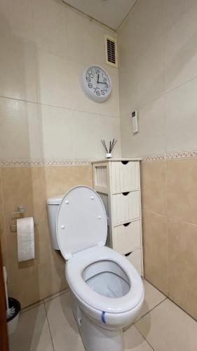 a bathroom with a toilet with a clock on the wall at Work and Rest Away From Home in Paterna