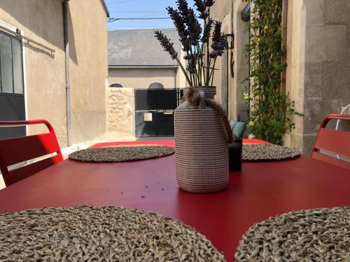 a red table with a vase on top of it at Gites De la Cour au Grenier in Chauvigny