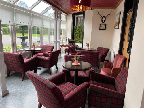 a restaurant with red chairs and tables and windows at Strathpeffer Hotel in Strathpeffer