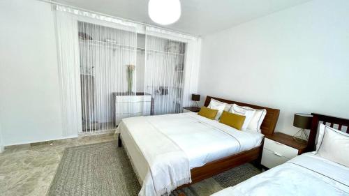 a white bedroom with two beds and a window at Los Naranjos close to Puerto Banus in Marbella