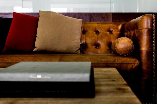 a brown leather couch with pillows and a table at Hotel Pax Guadalajara in Guadalajara