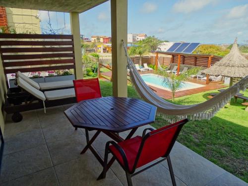 a hammock on a patio with a table and chairs at Los Caracoles in Punta Del Diablo