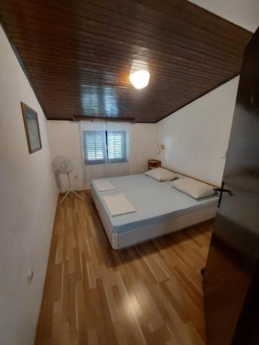 a bedroom with a bed and a wooden floor at Apartmani Vuksanović in Pag