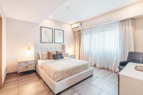 1 dormitorio blanco con 1 cama y 1 silla en Fully Serviced Apartment at Regatta Living II - 302, en Santo Domingo