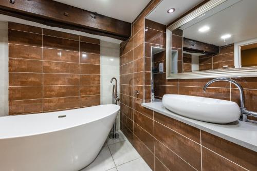 a bathroom with a large tub and a mirror at Spacious, luxury town centre Granary conversion in Stamford