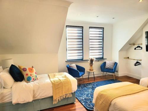 a bedroom with two beds and a blue chair at Spacious Six Bedrooms House By Sensational Stay Short Lets & Serviced Accommodation With 13 Beds, Free Parking, Free Wi-fi & Balcony in London
