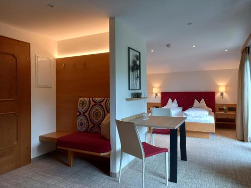 a hotel room with a bed and a table and a bedroom at Hotel Garni Erler in Mayrhofen
