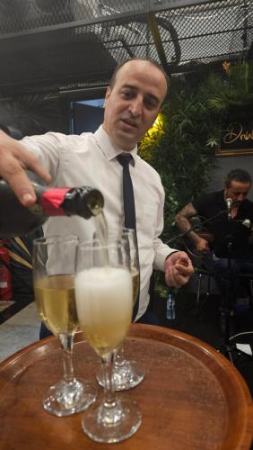 a man in a tie is pouring wine into two glasses at Dorana Hotel in Kérynia