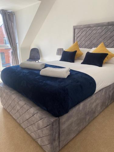 ein großes Bett mit blauen und gelben Kissen darauf in der Unterkunft Kingsway House - Brand New Spacious 4 Bed Home From Home in Derby