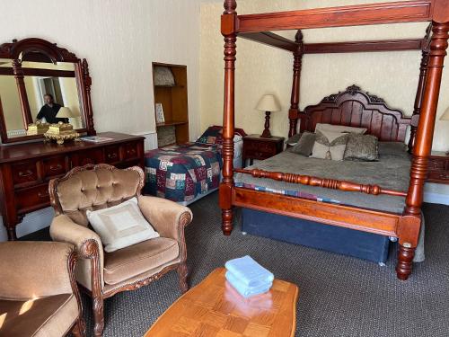 a bedroom with a canopy bed and a chair and a table at Strathpeffer Hotel in Strathpeffer