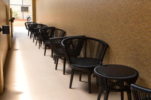a row of black chairs lined up against a wall at Nova Candolim By Sudhanand, Candolim in Candolim