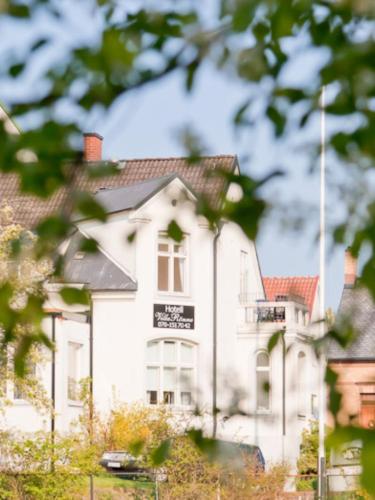 a white house with a sign on the side of it at Hotell Villa Rönne in Ängelholm