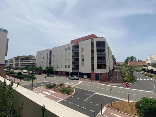un parking vide à côté d'un grand bâtiment dans l'établissement APPARTEMENT TYPE 2 NEUF +GRANDE TERRASSE, au Lavandou
