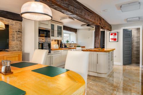 a kitchen with a wooden table and white cabinets at Spacious, luxury town centre Granary conversion in Stamford