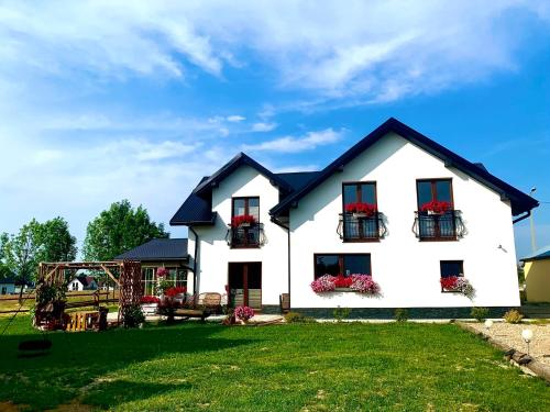 a white house with flower boxes on the windows at Zagroda na Borach in Jabłonka
